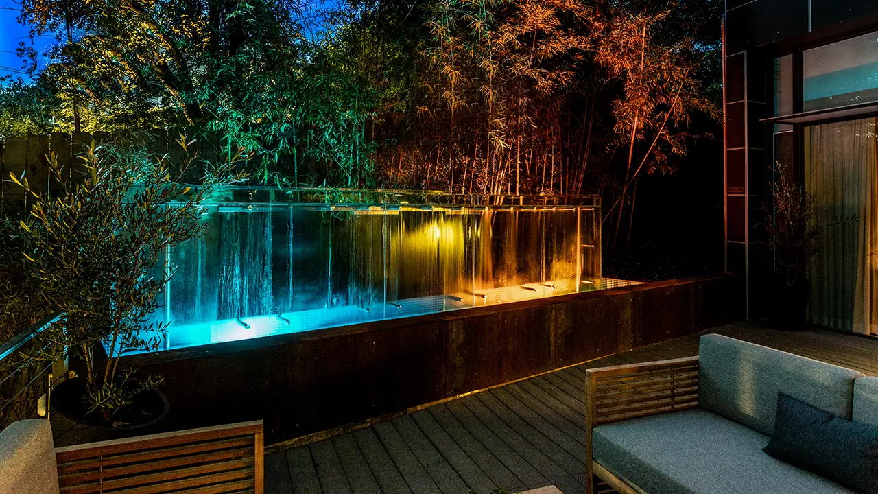 Frame Hotel Treehouse — glass water feature glowing after dark